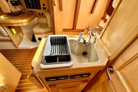 Blue Aweigh Yacht Photos Pics 2021 Tartan 345 yacht interior with compact kitchen sink and wooden cabinetry.