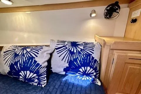 Blue Aweigh Yacht Photos Pics Cozy interior of 2021 Tartan 345 with blue floral pillows and wooden cabinetry.