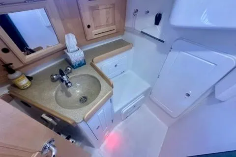 Blue Aweigh Yacht Photos Pics Compact bathroom in 2021 Tartan 345 yacht with sink, mirror, and storage cabinets.