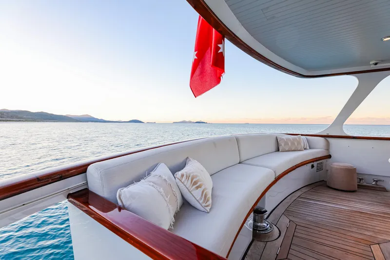 Kapal Yacht Photos Pics Luxurious 1971 Feadship yacht deck with elegant seating, ocean view, and red flag.