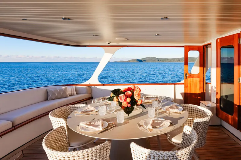 Kapal Yacht Photos Pics Luxurious 1971 Feadship yacht dining area with ocean view, elegant table setting, and floral centerpiece.