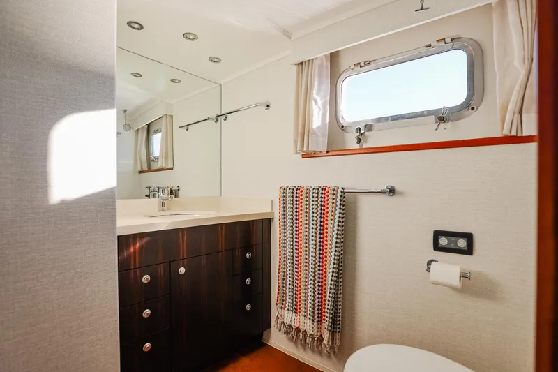 Kapal Yacht Photos Pics Luxurious yacht bathroom with modern fixtures, wooden cabinetry, and a colorful towel, Feadship 1971.