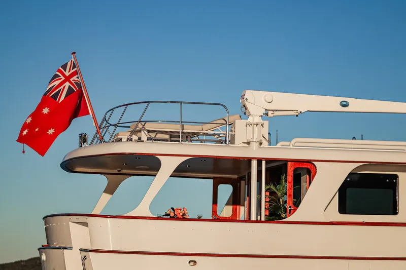 Kapal Yacht Photos Pics 1971 Feadship yacht with red flag, clear blue sky background.