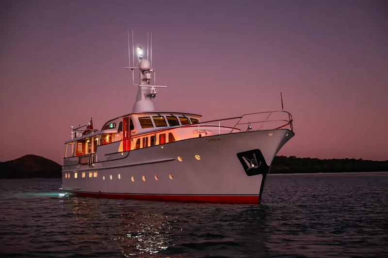 Kapal Yacht Photos Pics Classic 1971 Feadship yacht illuminated at sunset on calm waters.