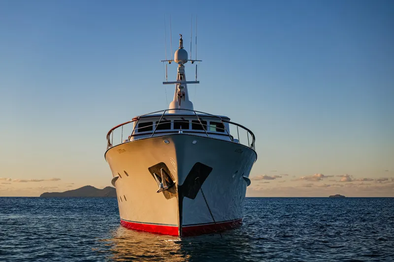 Kapal Yacht Photos Pics Front view of a 1971 Feadship yacht on calm sea at sunset.