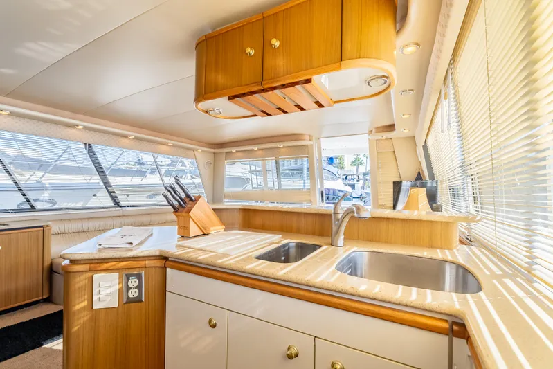 Hyve Yacht Photos Pics Luxurious kitchen interior of 2001 Bayliner 4788 Pilothouse yacht with wood cabinetry and dual sinks.