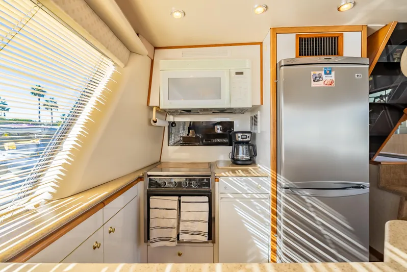Hyve Yacht Photos Pics 2001 Bayliner 4788 Pilothouse kitchen with microwave, stove, and refrigerator, illuminated by natural light.