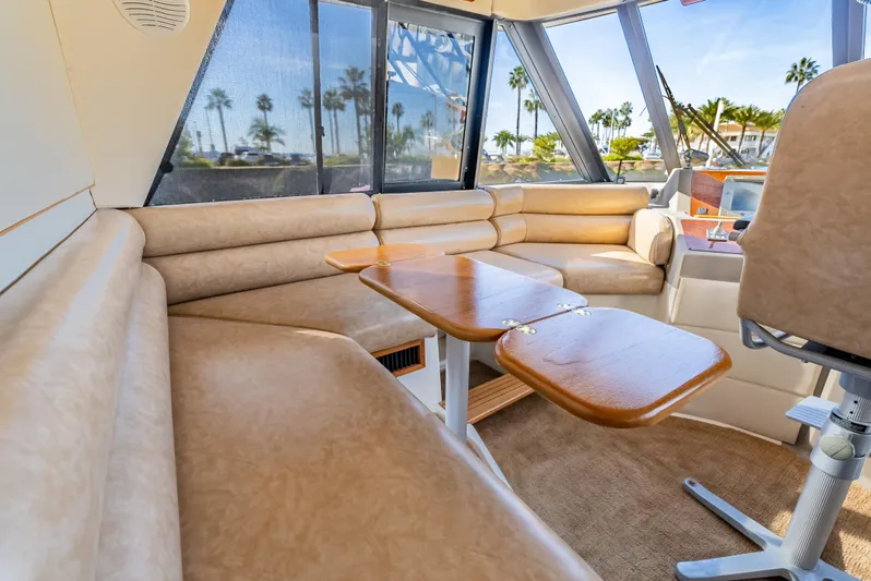 Hyve Yacht Photos Pics 2001 Bayliner 4788 Pilothouse interior with beige seating and wooden table.