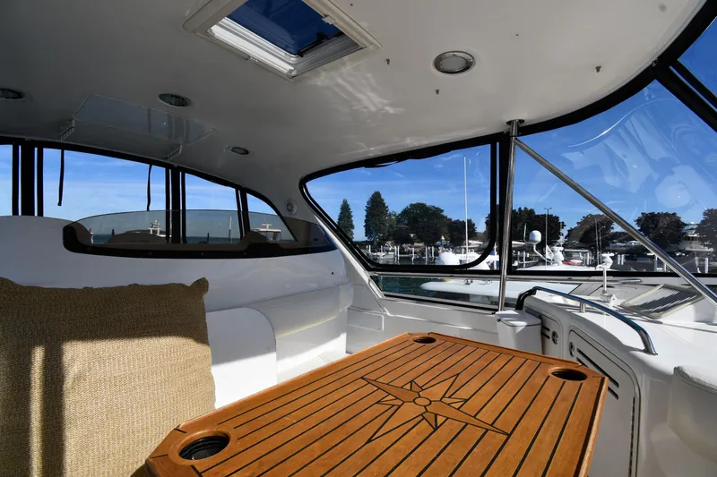 Nina Yacht Photos Pics Interior view of 2002 Sea Ray 480 Sedan Bridge yacht with wooden table and marina backdrop.