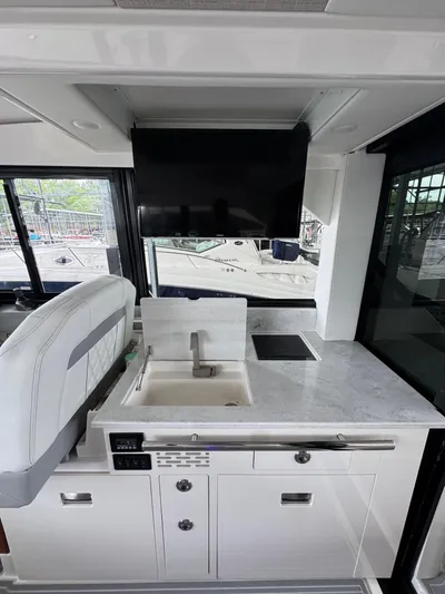  Yacht Photos Pics 2023 Regal 36 Grande Coupe interior with modern kitchenette and TV.