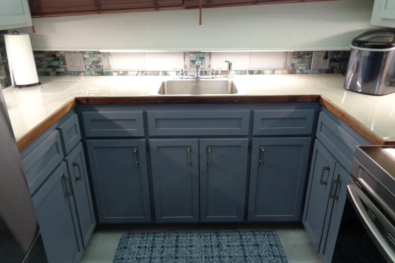 Ivory Lady Yacht Photos Pics Modern kitchen with blue cabinets, stainless steel appliances, and a sleek countertop on a 1987 Hatteras yacht.