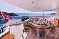 Luxurious Benetti Custom 2008 yacht deck with elegant dining setup and scenic ocean view.