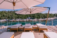 Luxurious Benetti Custom 2008 yacht deck with sun loungers and umbrellas, overlooking serene waters.