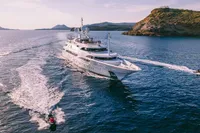 Luxurious 2008 Benetti Custom yacht cruising near scenic coastline with jet skis.