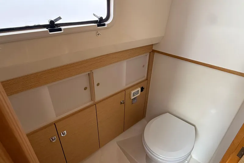  Yacht Photos Pics Compact bathroom in 2013 Fjord 40' Open yacht with wooden cabinets and a window.