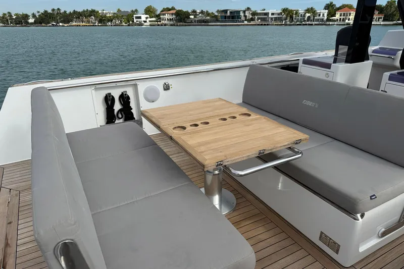  Yacht Photos Pics Luxurious seating area on 2013 Fjord 40' Open yacht with wooden table and waterfront view.