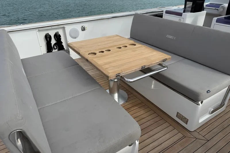  Yacht Photos Pics Luxury seating area on 2013 Fjord 40' Open yacht with wooden table and gray cushions.