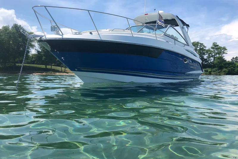  Yacht Photos Pics 2018 Monterey 295 Sport Yacht on clear water, anchored near a lush shoreline.