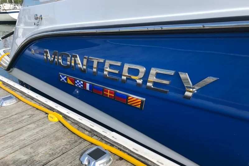  Yacht Photos Pics 2018 Monterey 295 Sport Yacht with nautical flags on blue hull.