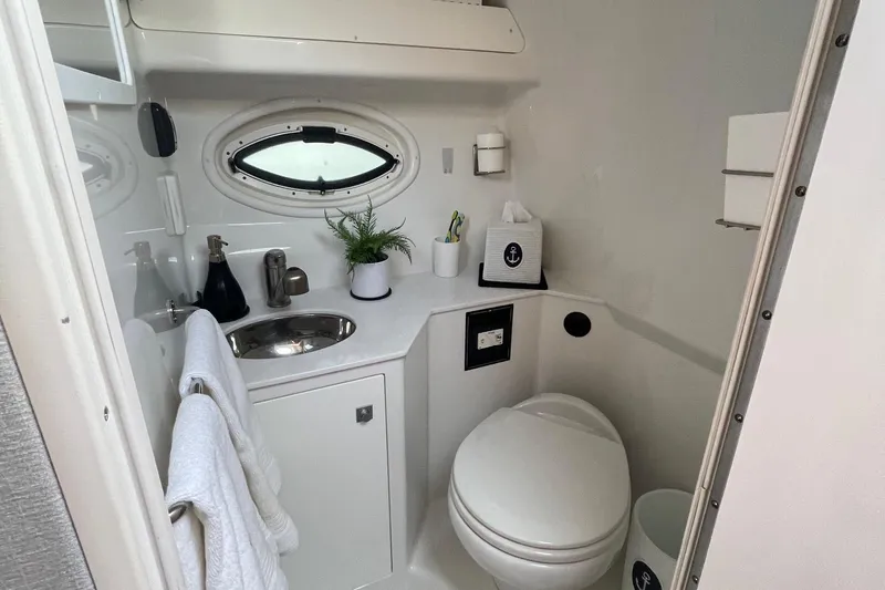  Yacht Photos Pics Compact bathroom in 2018 Monterey 295 Sport Yacht with sink, toilet, and porthole window.