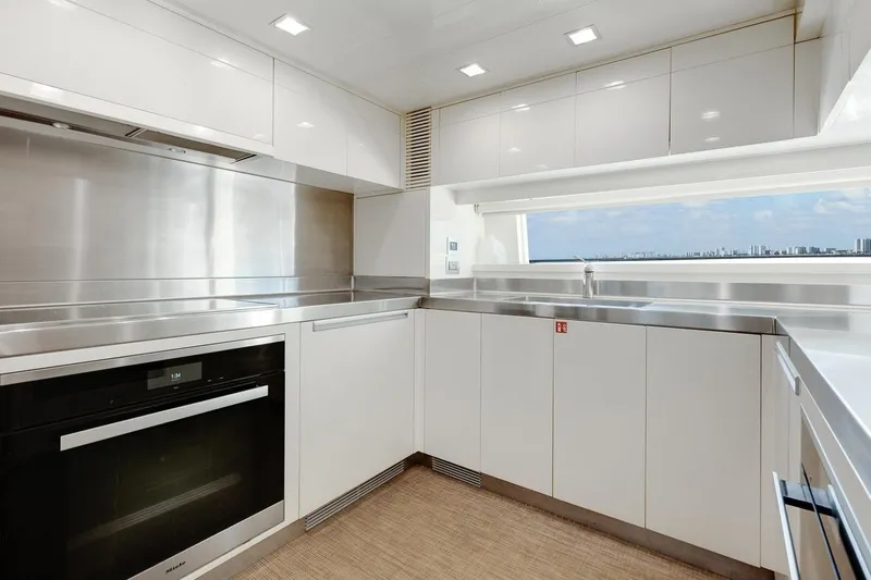 Amanecer Yacht Photos Pics Modern kitchen interior on 2009 Azimut 105 yacht, featuring sleek white cabinetry and stainless steel appliances.