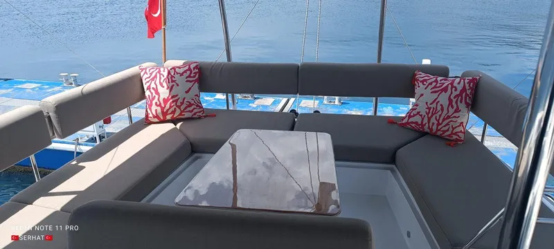 Hayat Yacht Photos Pics Nautitech 46 Fly 2021 yacht seating area with cushions and table, overlooking water.