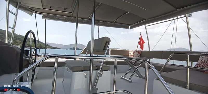 Hayat Yacht Photos Pics Nautitech 46 Fly 2021 yacht deck with seating, ocean view, and red flag.