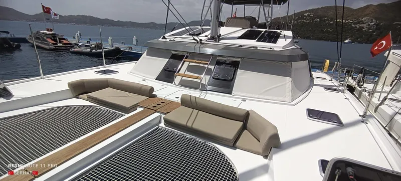 Hayat Yacht Photos Pics 2021 Nautitech 46 Fly catamaran with spacious deck and seating, docked in a scenic marina.