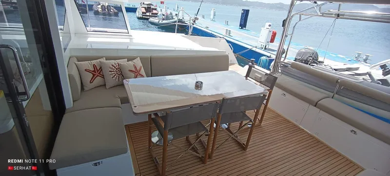 Hayat Yacht Photos Pics Nautitech 46 Fly 2021 yacht deck with seating and table, overlooking marina.