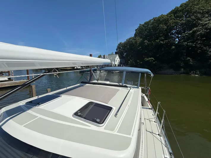 North Sound Yacht Photos Pics 2024 Tartan 455 sailboat docked by a serene waterfront with lush greenery.