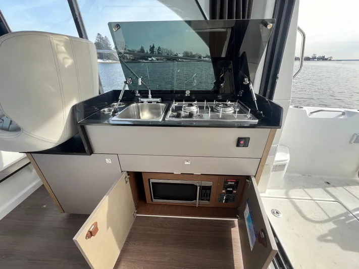  Yacht Photos Pics Compact kitchen area on 2020 Beneteau Antares 9 boat with stove, sink, and microwave.