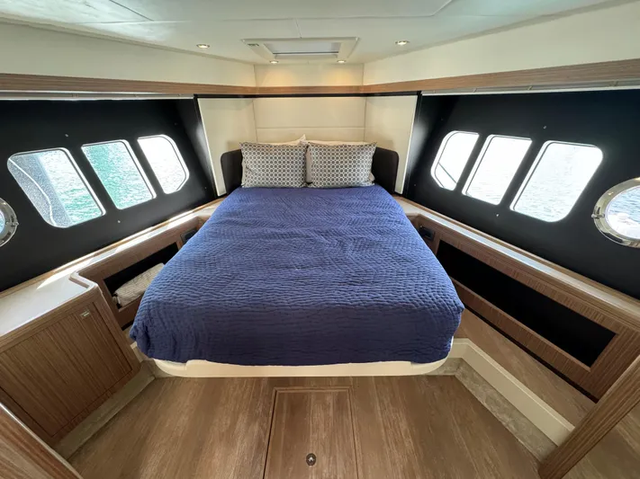  Yacht Photos Pics Luxurious bedroom interior of 2017 Absolute 50 Fly yacht with blue bedding and large windows.