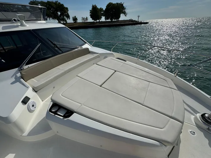  Yacht Photos Pics 2017 Absolute 50 Fly yacht with sunbathing area, overlooking serene water and distant trees.