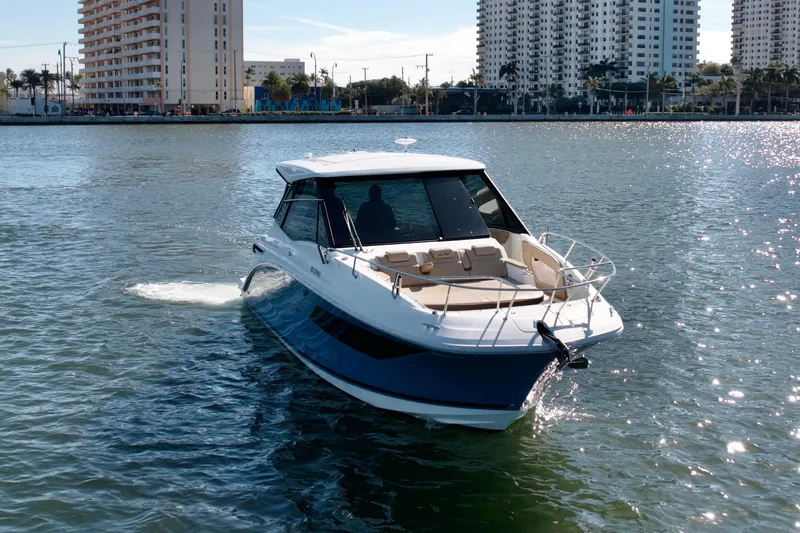  Yacht Photos Pics 2022 Sea Ray Sundancer 320 cruising on a sunny day near urban waterfront.