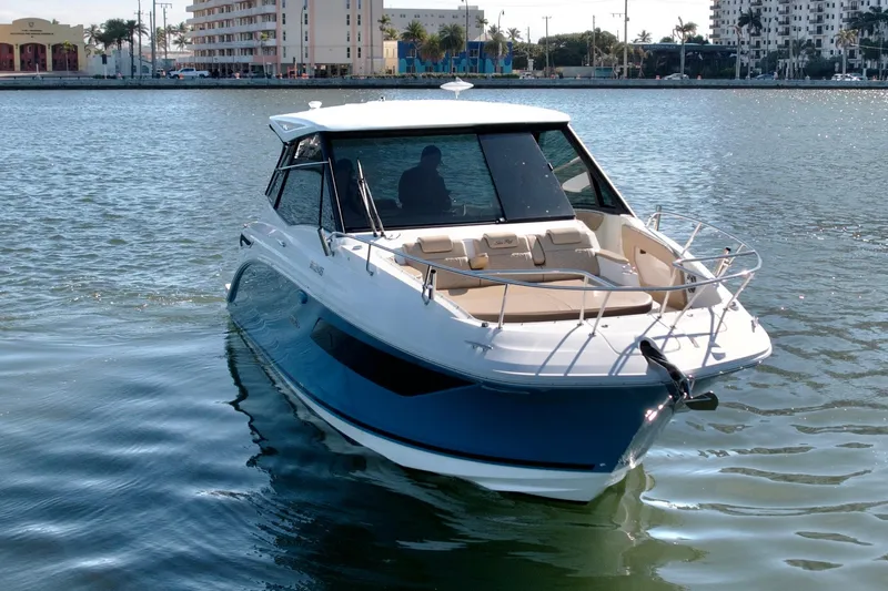 Yacht Photos Pics 2022 Sea Ray Sundancer 320 boat on calm water, urban backdrop.