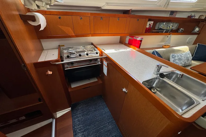 Mi Fuego Yacht Photos Pics 2017 Beneteau Oceanis 37 yacht interior kitchen with stove, sink, and wooden cabinetry.
