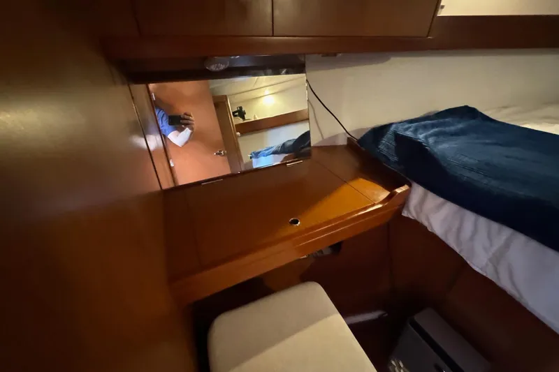 Mi Fuego Yacht Photos Pics Cozy cabin interior of 2017 Beneteau Oceanis 37 sailboat with wooden furnishings and blue bedding.