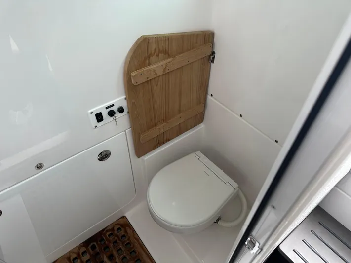  Yacht Photos Pics 2023 Everglades 395 Center Console boat bathroom with toilet and wooden accents.