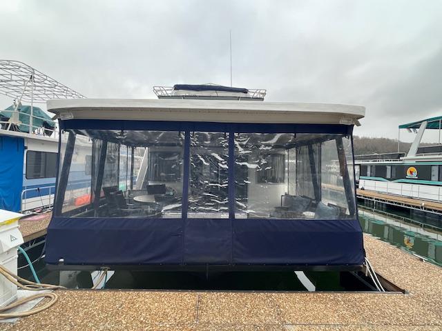Houseboat with blue canopy docked at marina, Funtime 16x72 model, year 2000.