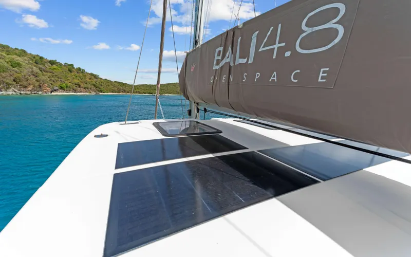 Always Sunday Yacht Photos Pics 2022 Bali 4.8 catamaran sailing in clear blue waters near a lush green island.