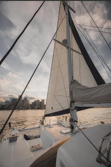 Blue Star Yacht Photos Pics Sailing yacht Privilege 43, 1993 model, on water with city skyline at sunset.