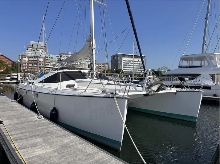 Blue Star Yacht Photos Pics Sailing catamaran Privilege 43, 1993 model, docked at marina with cityscape background.