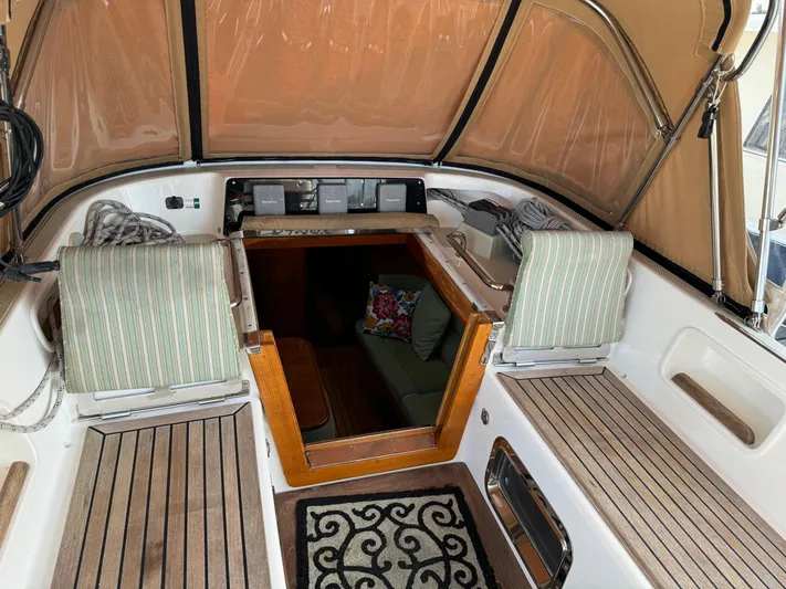 Shearwater Yacht Photos Pics Interior view of a 2008 Hylas 46 sailboat cockpit with striped seating and wooden accents.