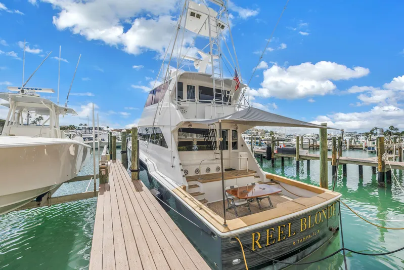 Reel Blonde Yacht Photos Pics Luxury 1999 Viking 72 Enclosed Bridge yacht docked at marina under blue sky.