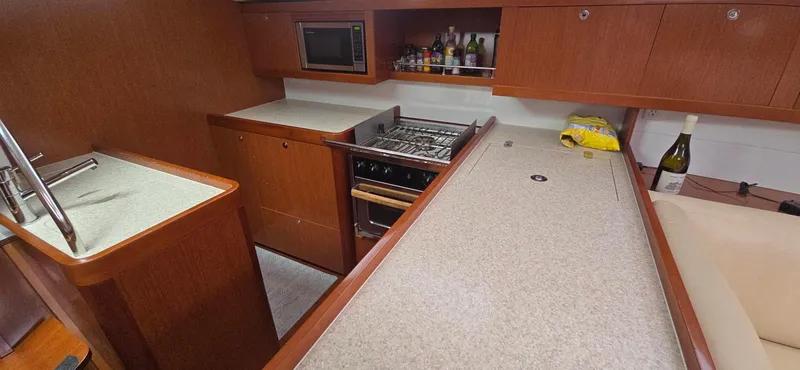 Diamant Noir Yacht Photos Pics Modern kitchen in 2011 Beneteau Oceanis 46 yacht with stove, microwave, and wooden cabinetry.