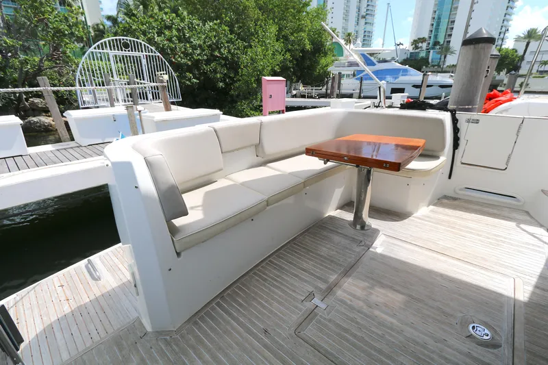  Yacht Photos Pics Outdoor seating area on 2014 Azimut Magellano 43 yacht, featuring a wooden table and cushioned bench.