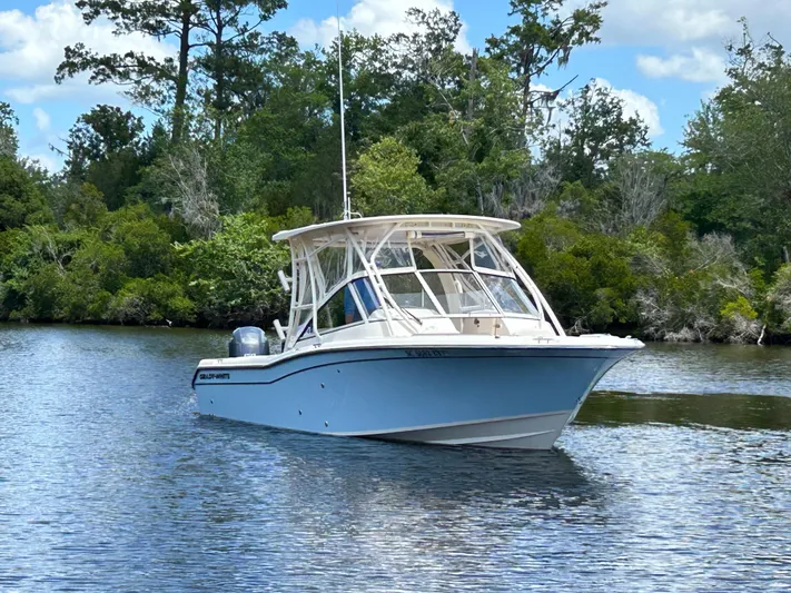  Yacht Photos Pics 2022 Grady-White 255 FREEDOM boat on calm water, surrounded by lush greenery.