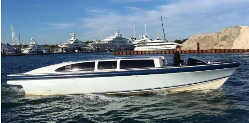  Yacht Photos Pics 2008 Goetz Custom Boats 33' Limo Tender cruising in a marina with yachts in the background.