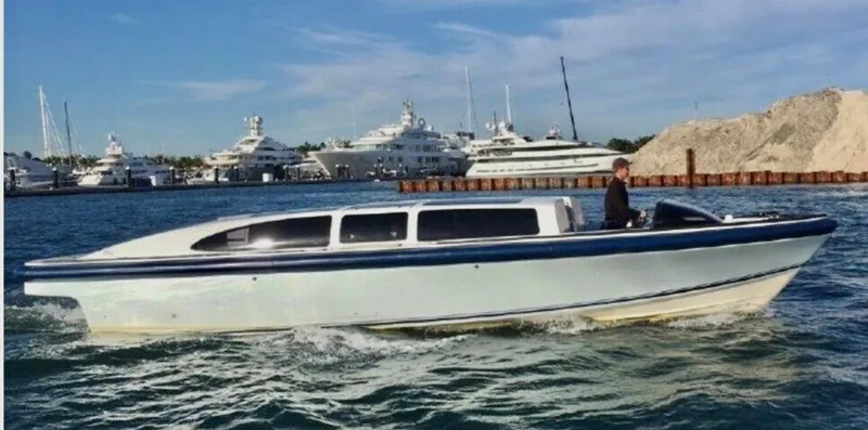  Yacht Photos Pics 2008 Goetz Custom Boats 33' Limo Tender cruising in a marina with yachts in the background.