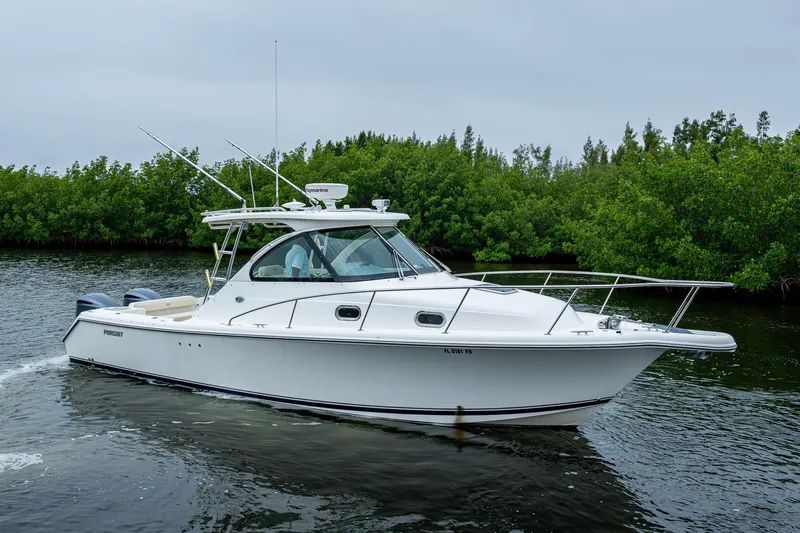  Yacht Photos Pics 2008 Pursuit OS 315 Offshore boat on calm water, surrounded by lush greenery.